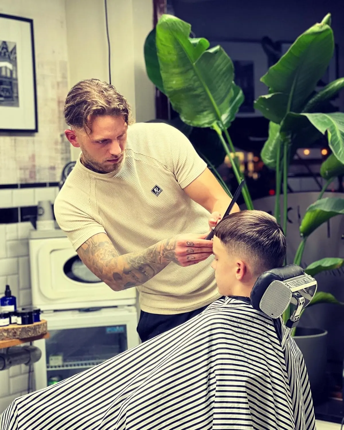 Barbier knipt een klant, met planten op de achtergrond